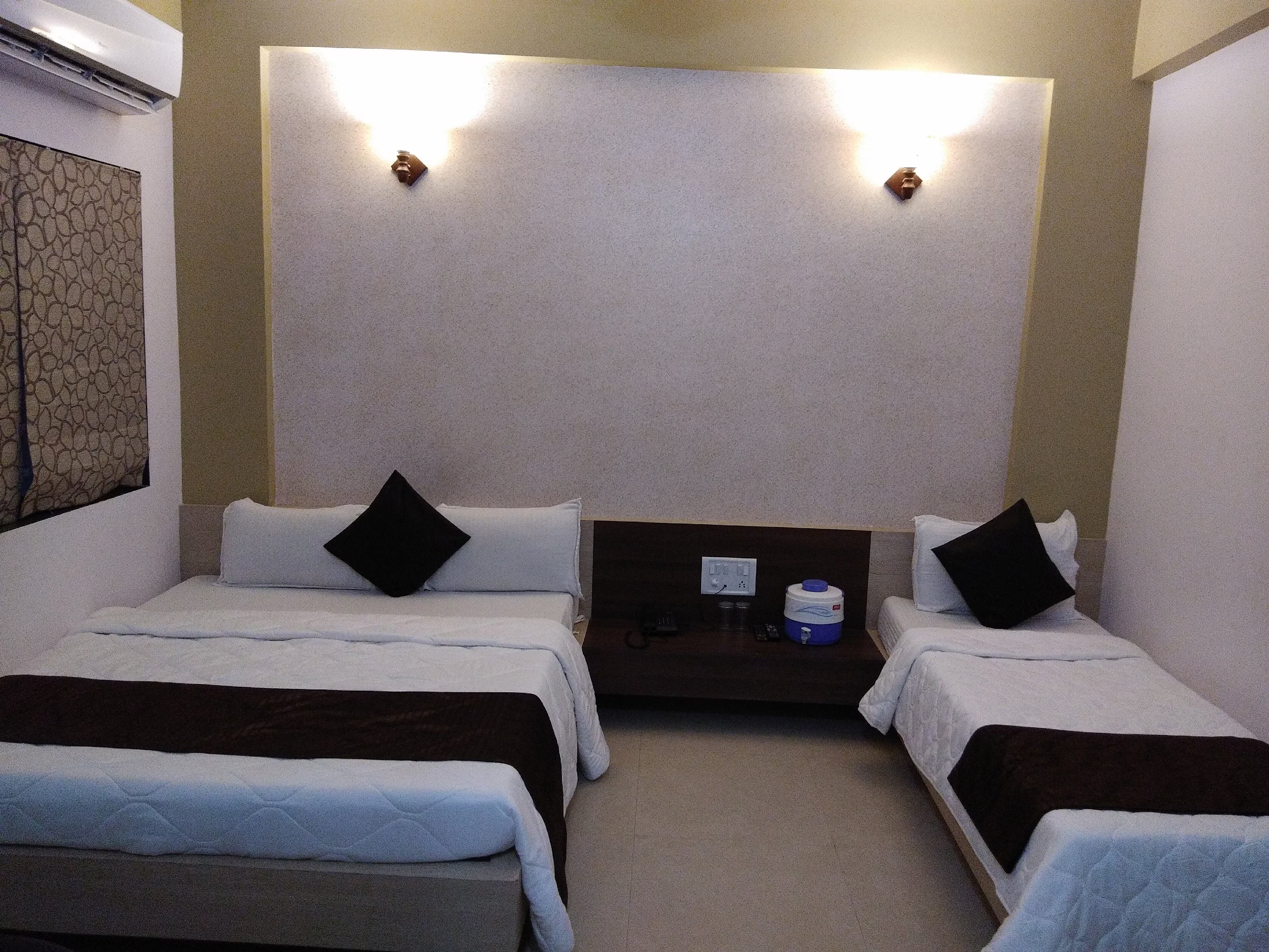 Well-appointed triple bed room at Hotel Somnath Atithigruh, ensuring a comfortable and airy stay for three guests.